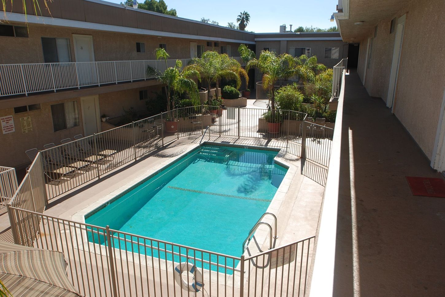 Swimming pool in a courtyard surrounded by apartments and a wrought iron fence.