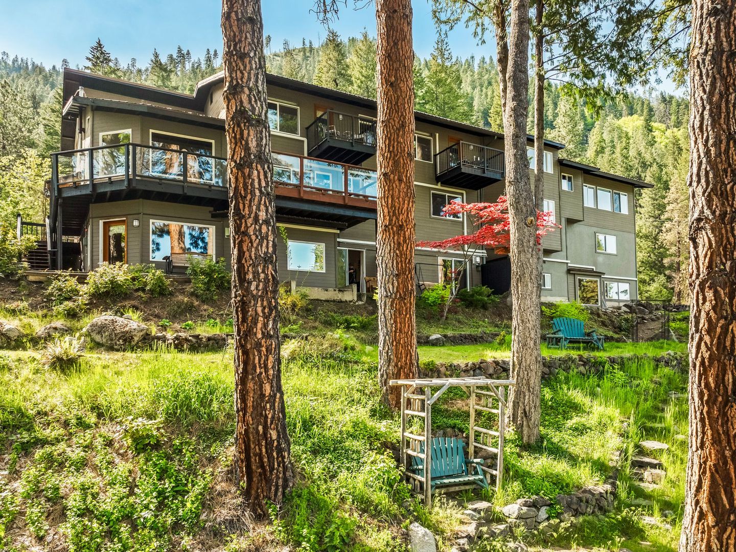 Multi-story hotel nestled in a forest, featuring balconies, windows, and a lush green landscape.