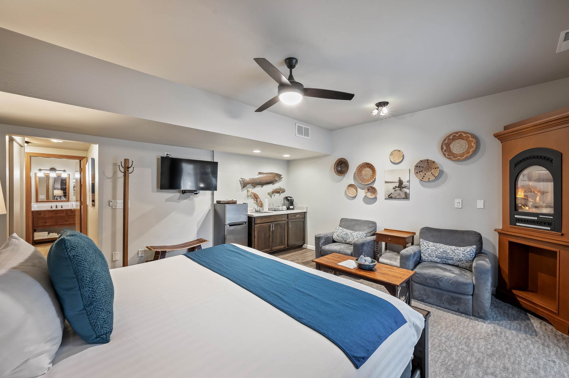Hotel room with bed, chairs, TV, and decorative wall art.