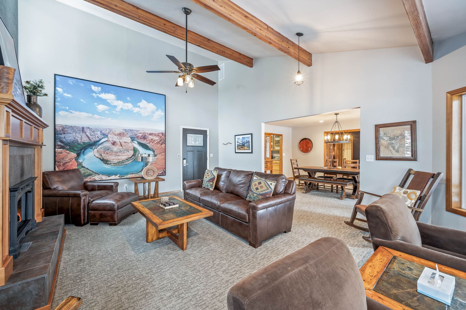 Living room with brown leather furniture, large landscape art, and exposed beams.