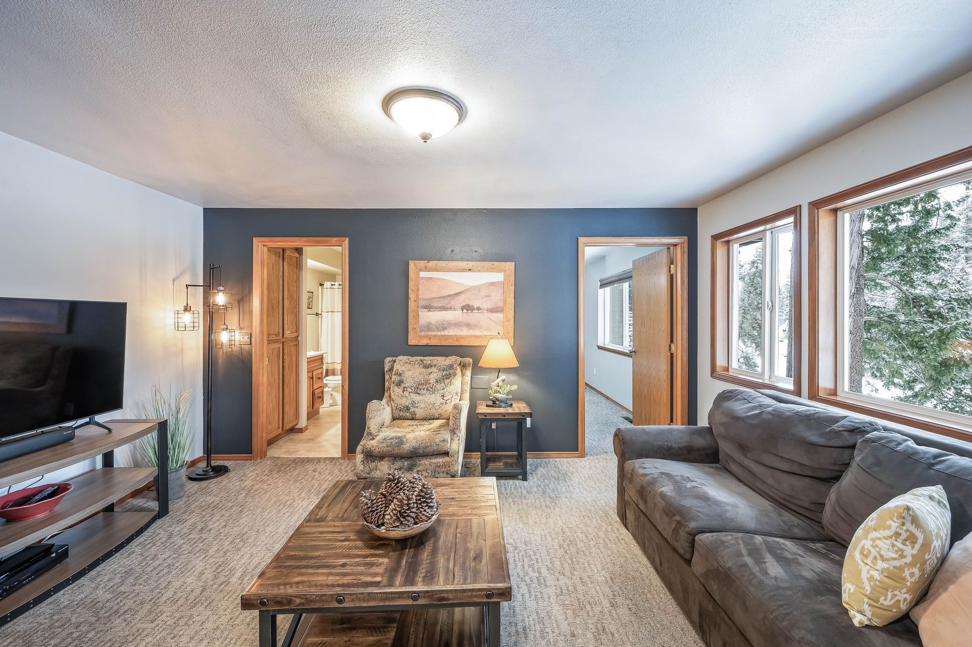 Living room with gray sofa, TV, and blue accent wall. Brown wooden coffee table and beige carpet.