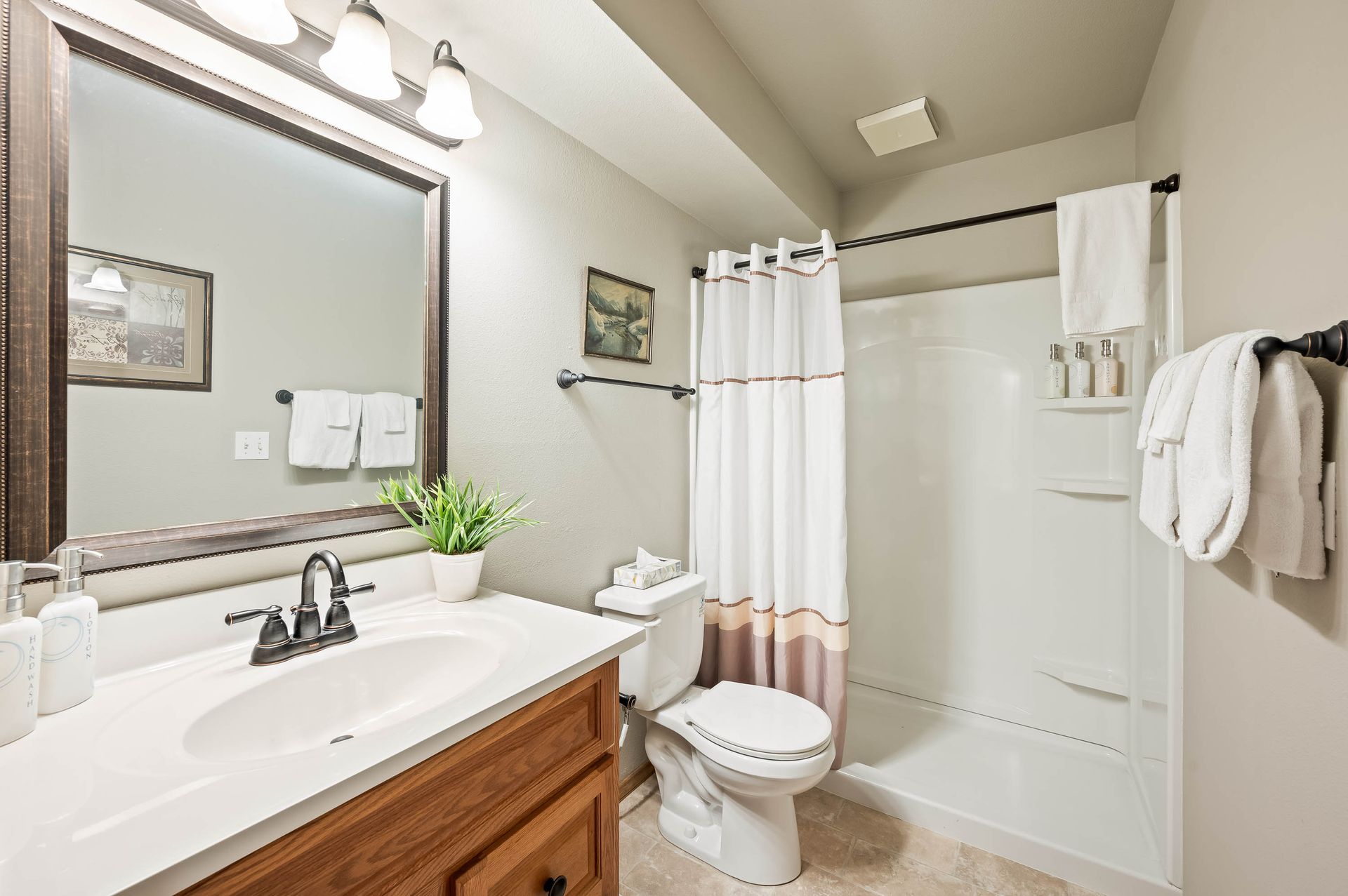 Bathroom with a vanity, toilet, and shower/tub. Beige walls, white fixtures, brown wood cabinet.