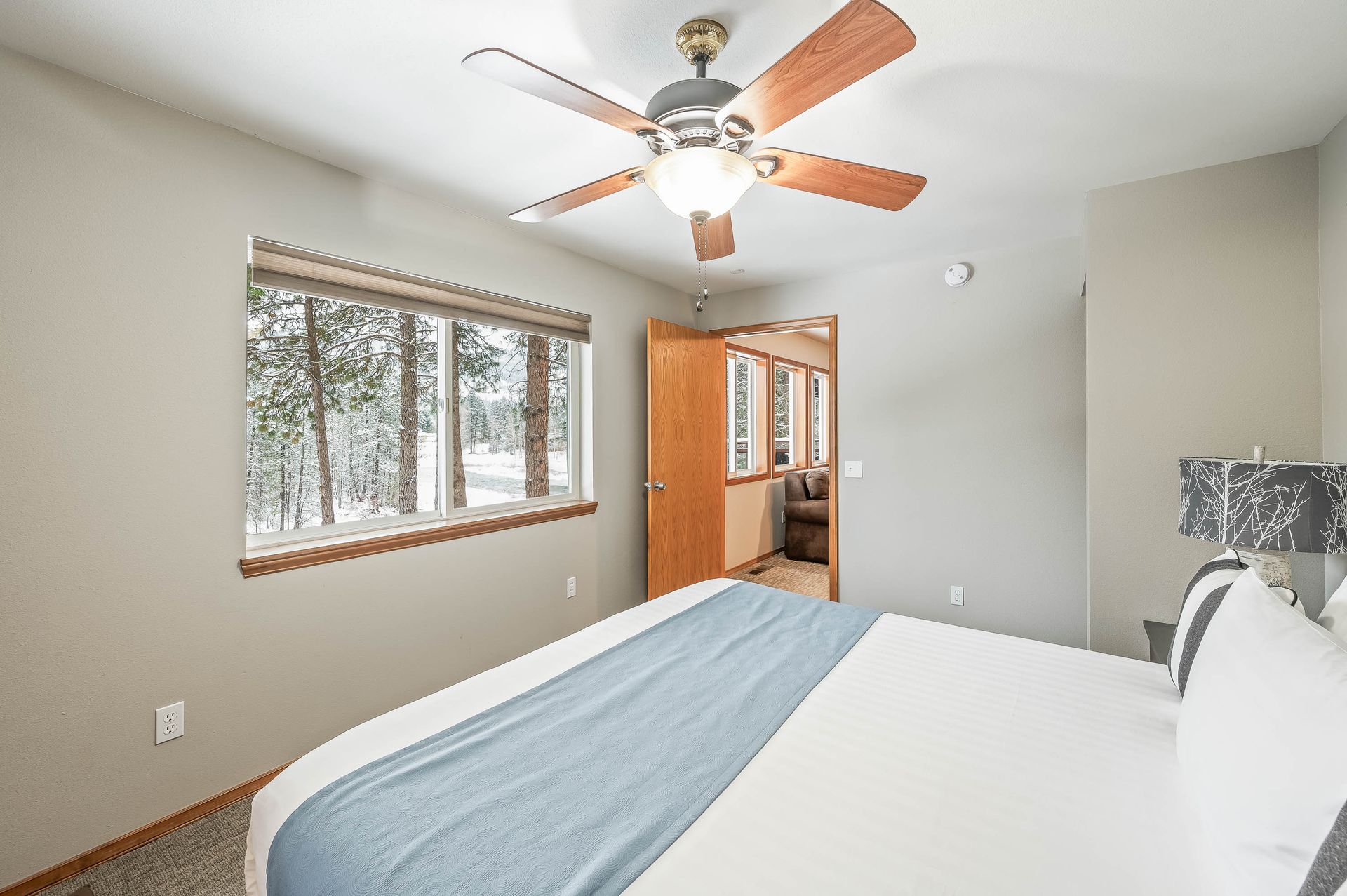 Bedroom with a bed, a window, and a door leading to another room. A ceiling fan is installed.