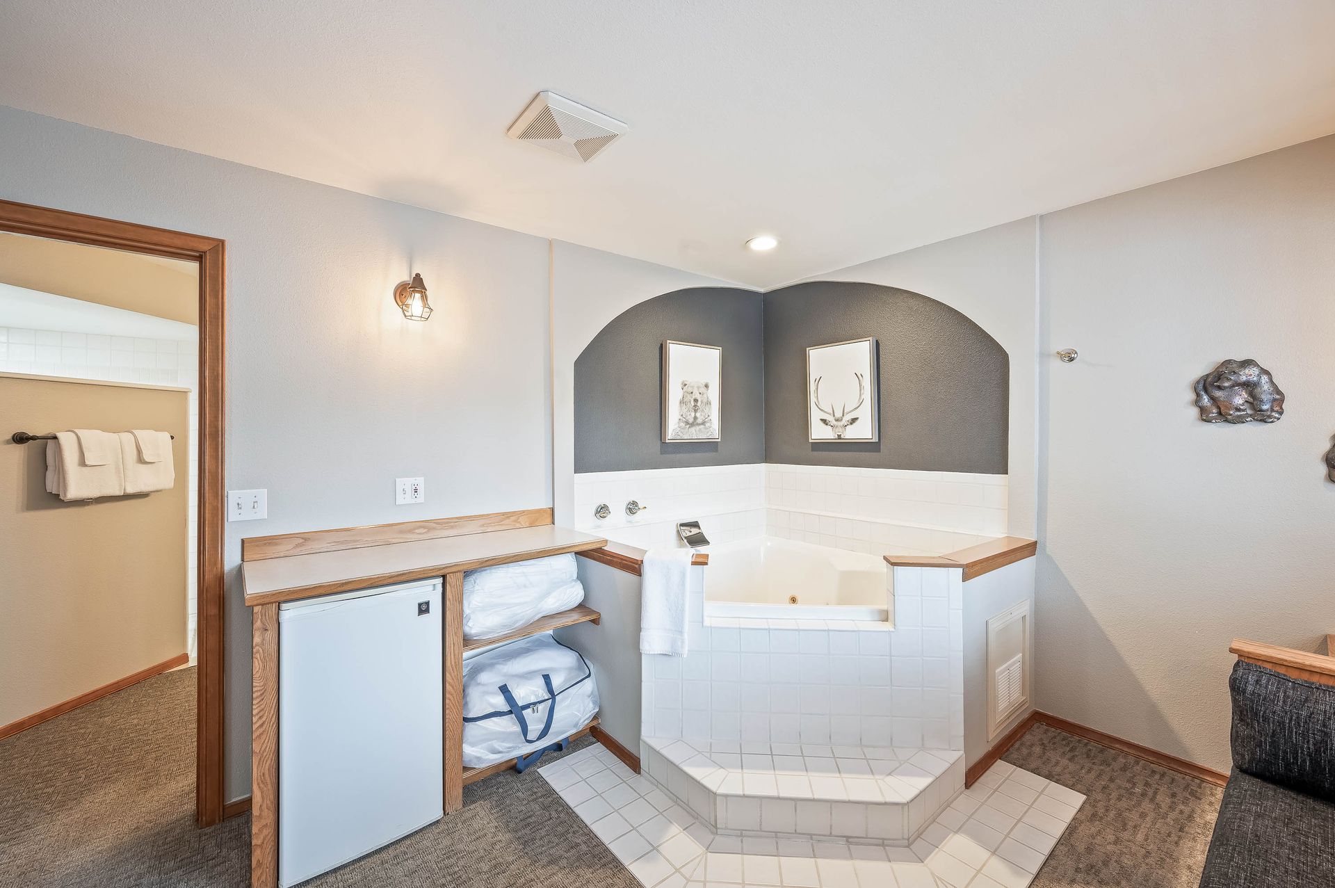 Bathroom with built-in jacuzzi tub, grey walls, towels, and wood accents.