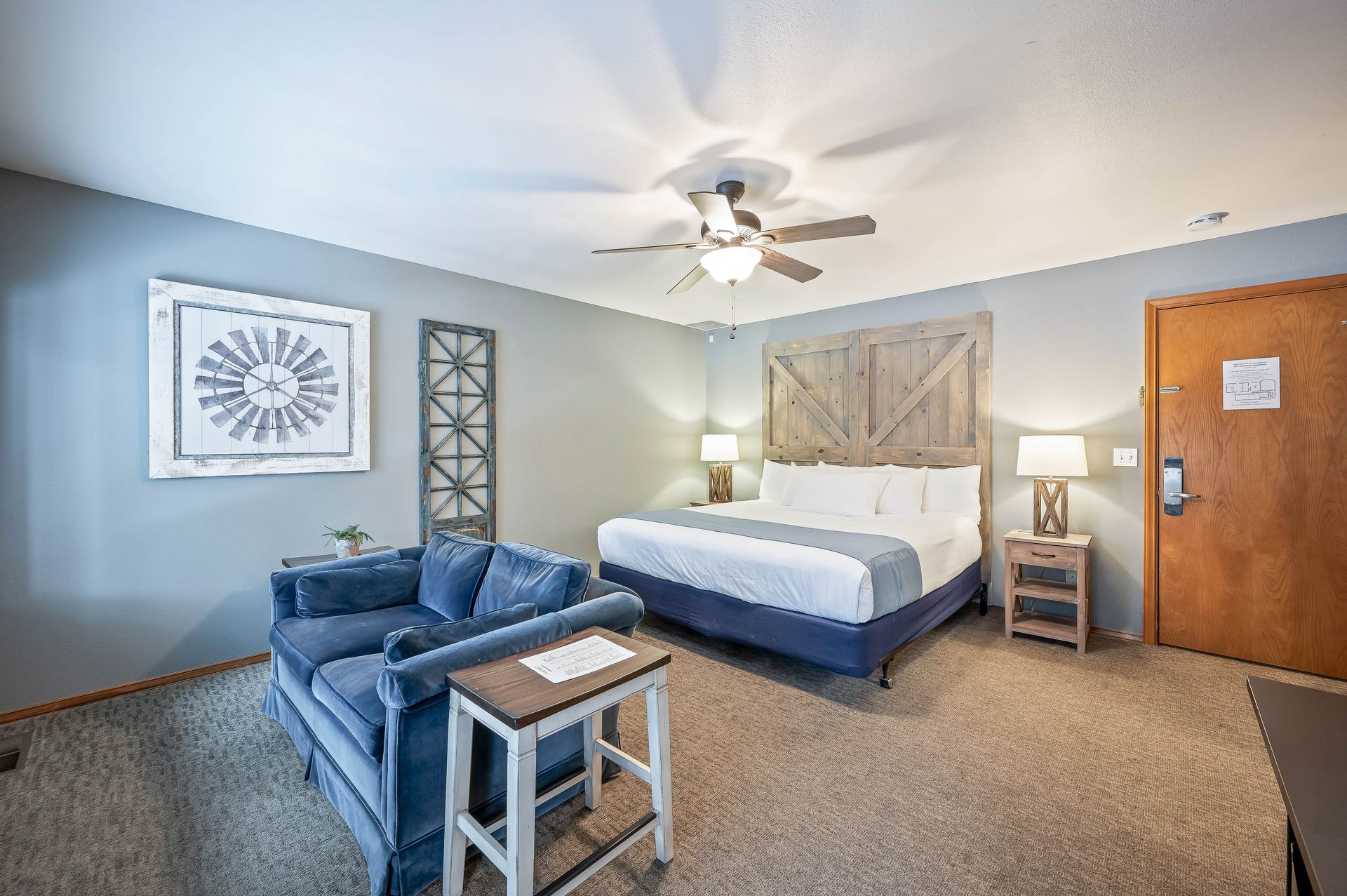 Hotel room with a bed, sofa, side table, and rustic decor.