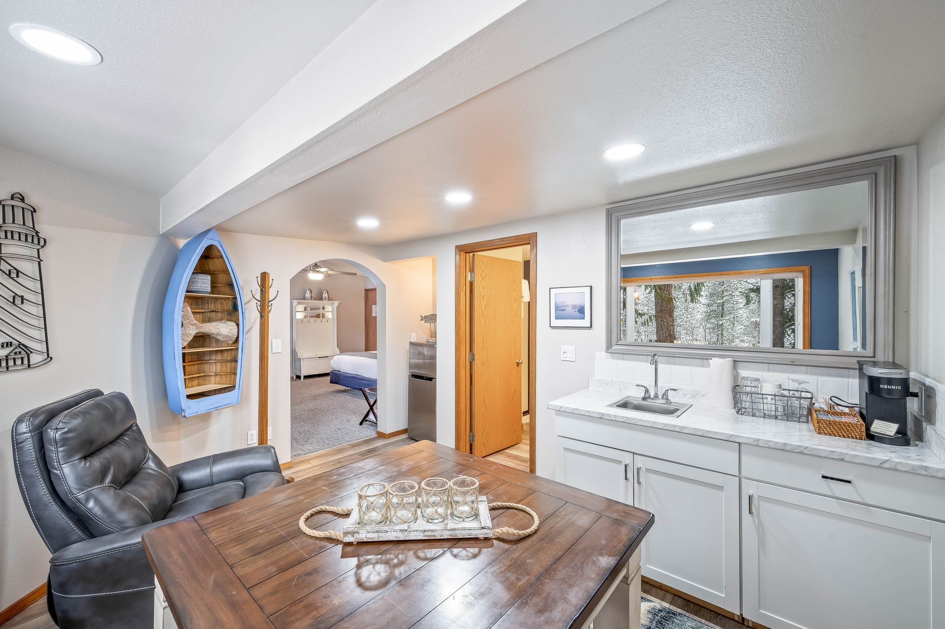 Interior of a room with a seating area, kitchenette, and doorway to another room.