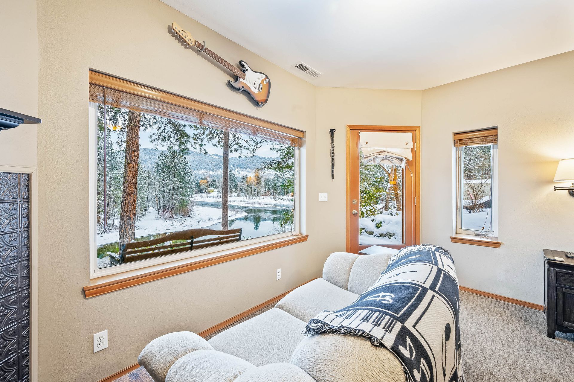 Cozy living room with snowy window view, beige walls, recliner, and guitar.