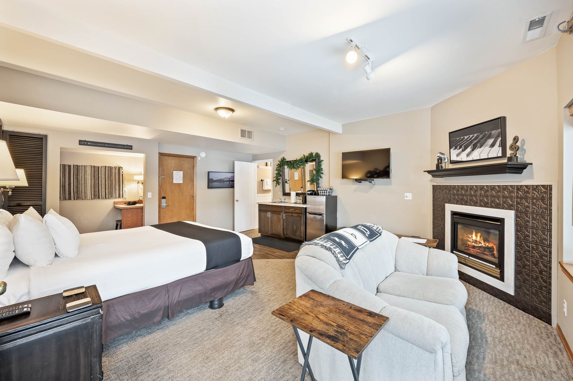 Cozy hotel room with a bed, fireplace, sofa, and small wooden table.