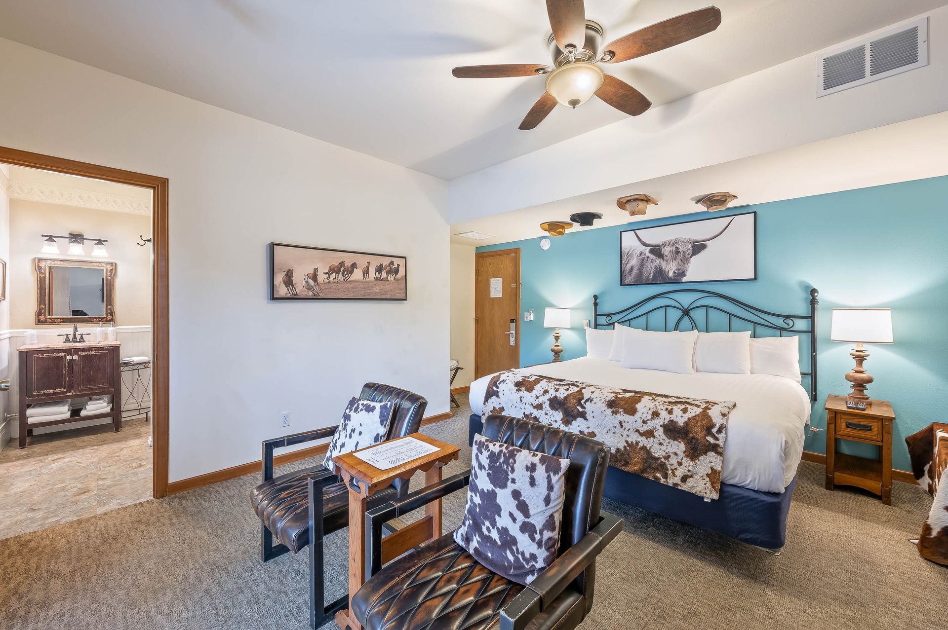 Bedroom with a king bed, sitting area, and en suite bathroom. Blue accent wall, western decor.