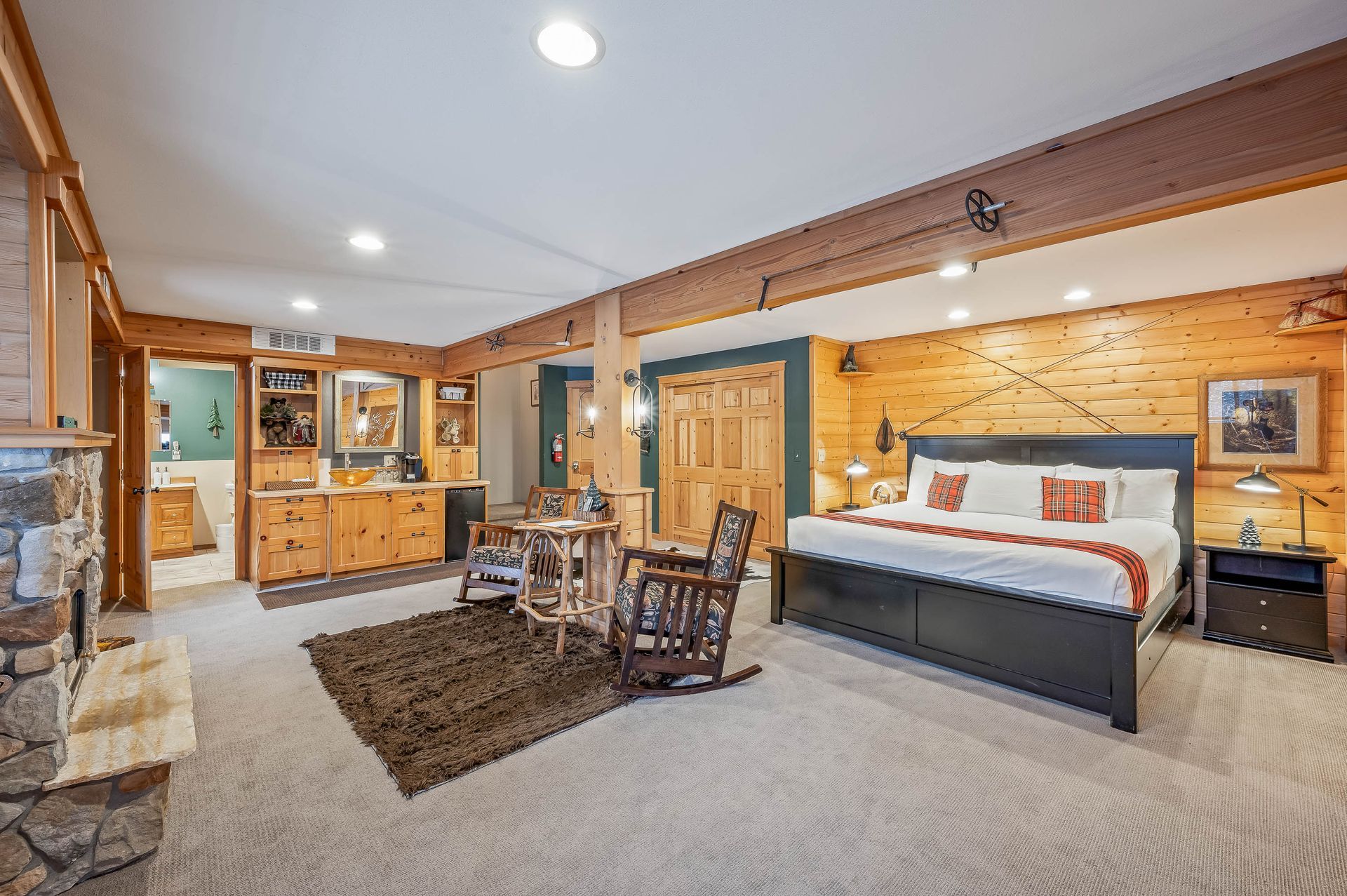 Spacious bedroom with king bed, fireplace, and vanity, rustic wood and cream tones.