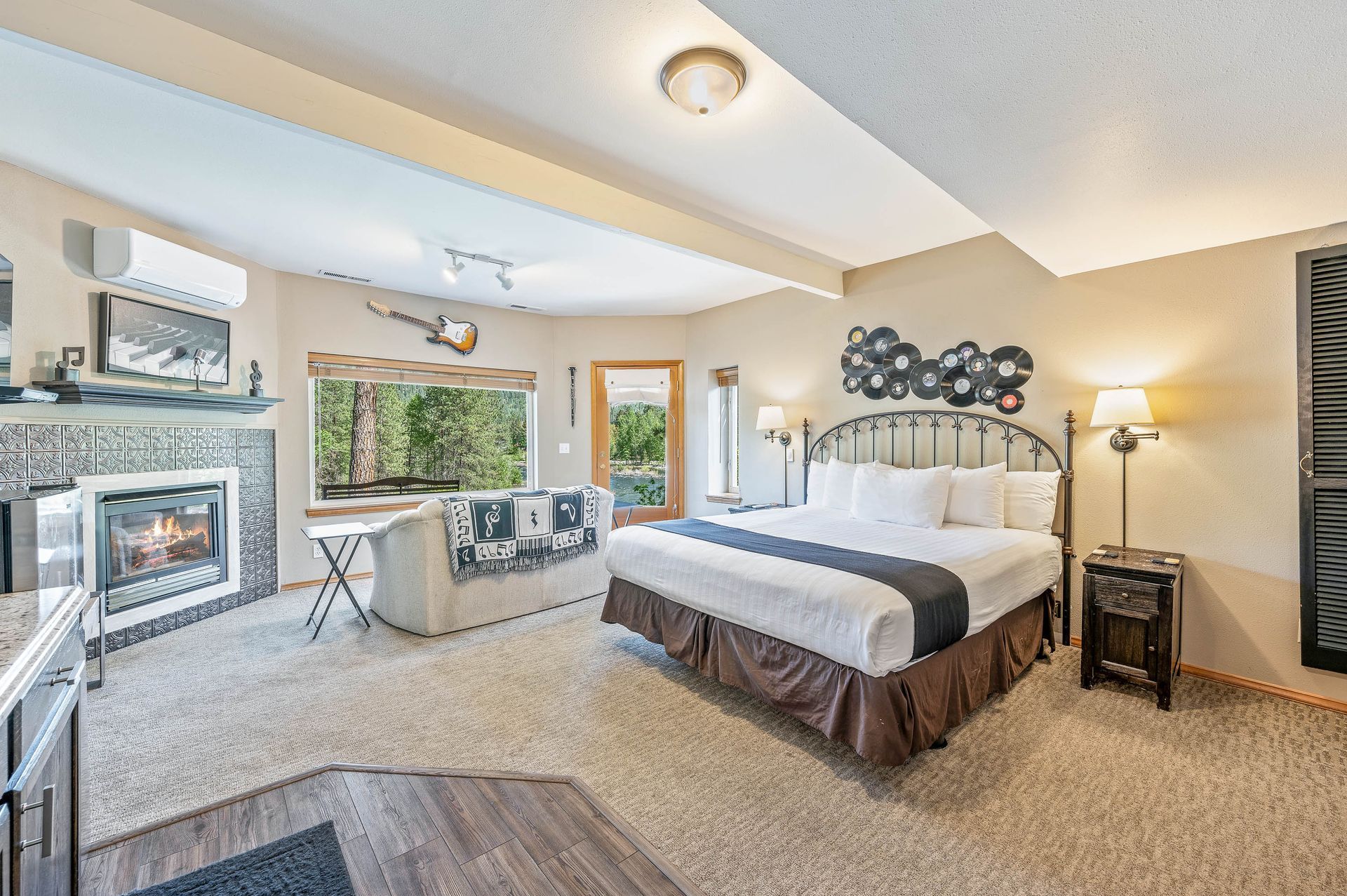 Cozy bedroom with fireplace, king bed, sofa, and access to a view. Neutral tones, light-colored carpet.