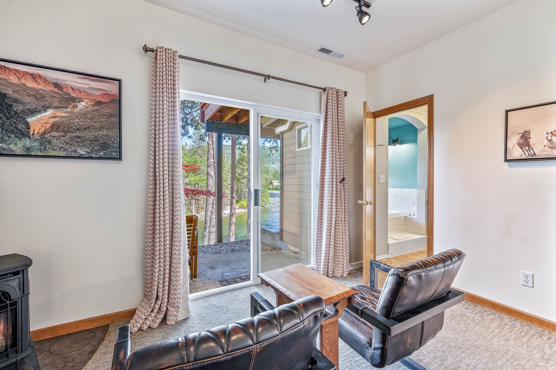 Cozy room with sliding glass door to a patio, two armchairs, a fireplace, and artwork.