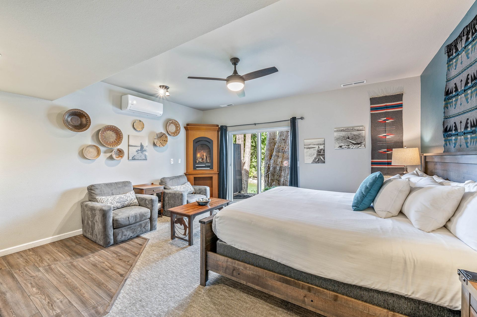 Bedroom with a king-sized bed, seating area, and a fireplace, with a sliding door leading outside.