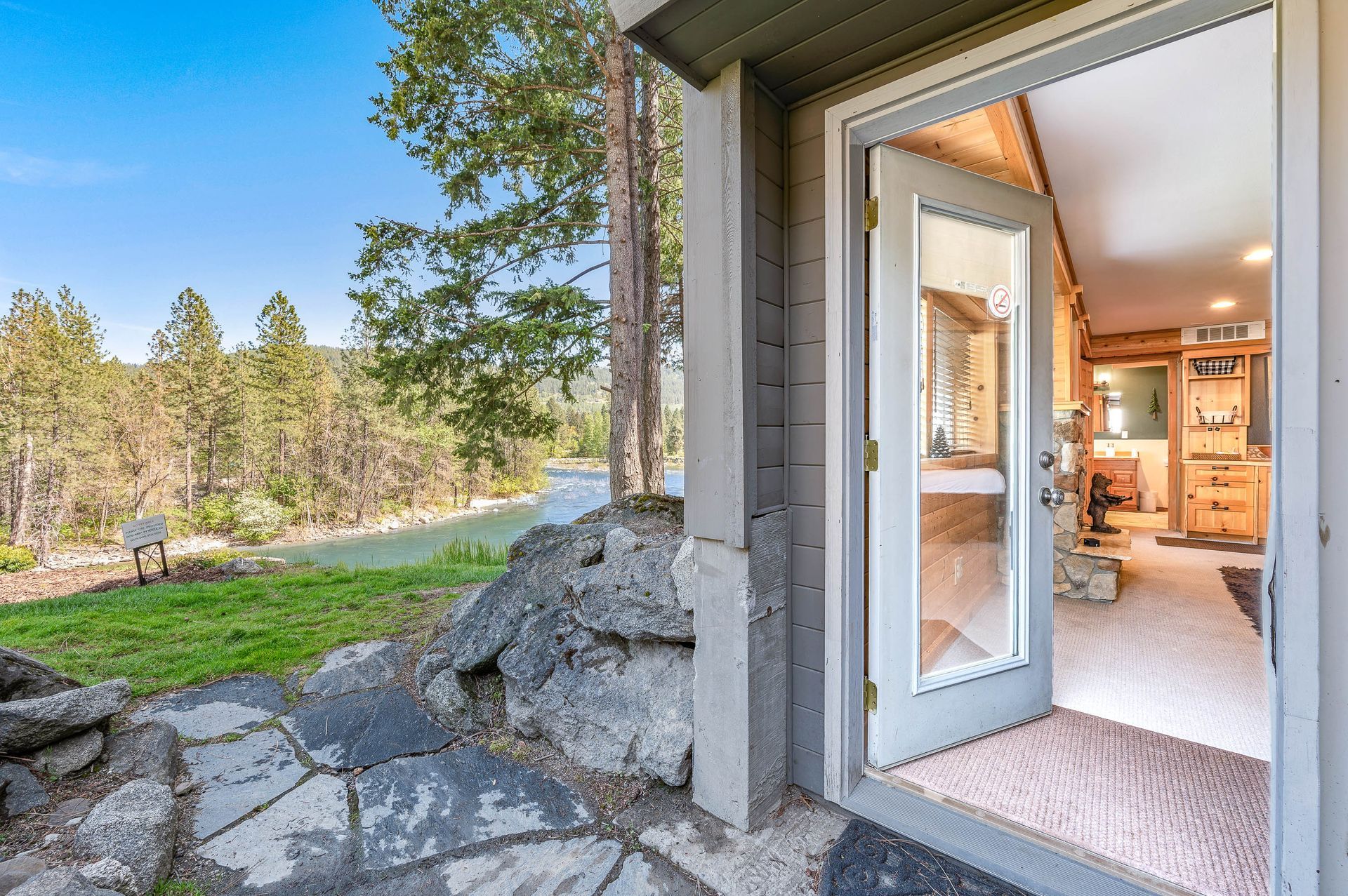 Open doorway overlooking a river and trees, leading into a rustic interior.
