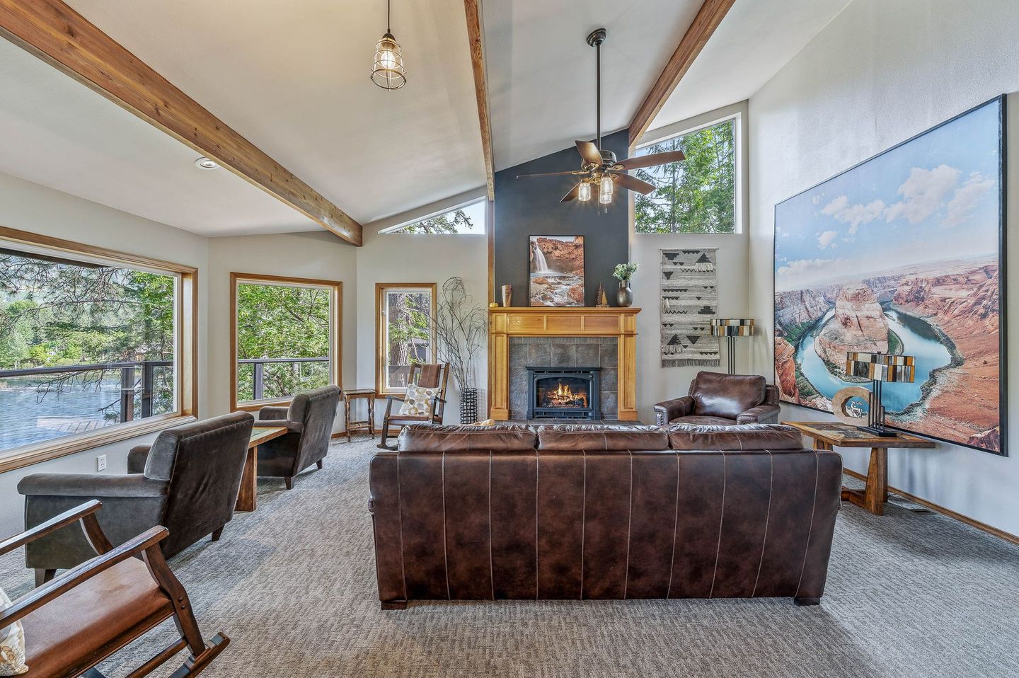 Living room with fireplace, brown leather sofa, large artwork, wood beams.