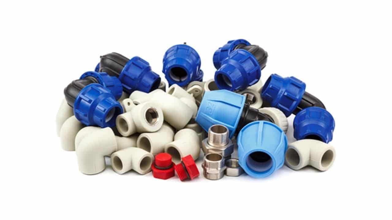 Uma pilha de tubos e conexões de plástico em um fundo branco.