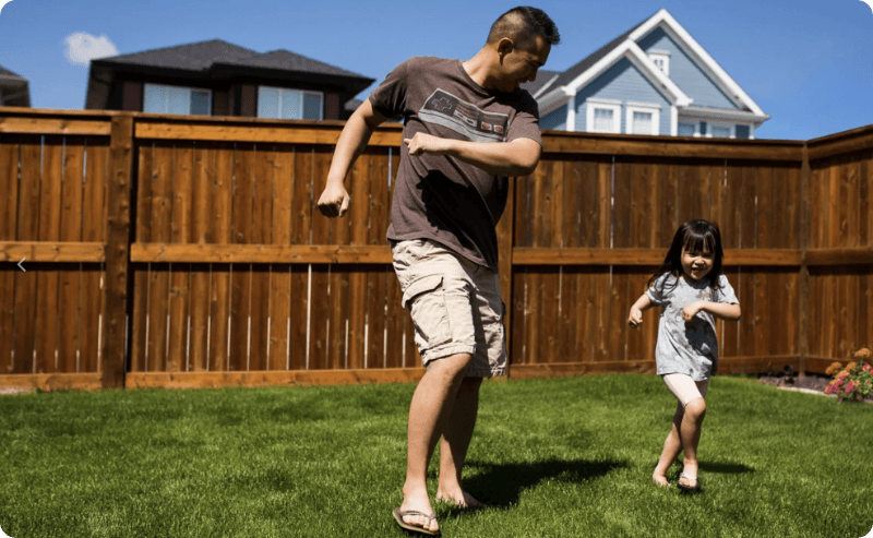 a man and a little girl are playing frisbee in a backyard