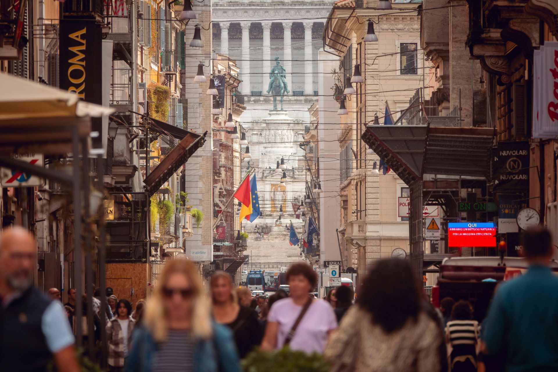 Busy street in Rome with a view of the Monument to Victor Emmanuel II at the end of Via del Corso