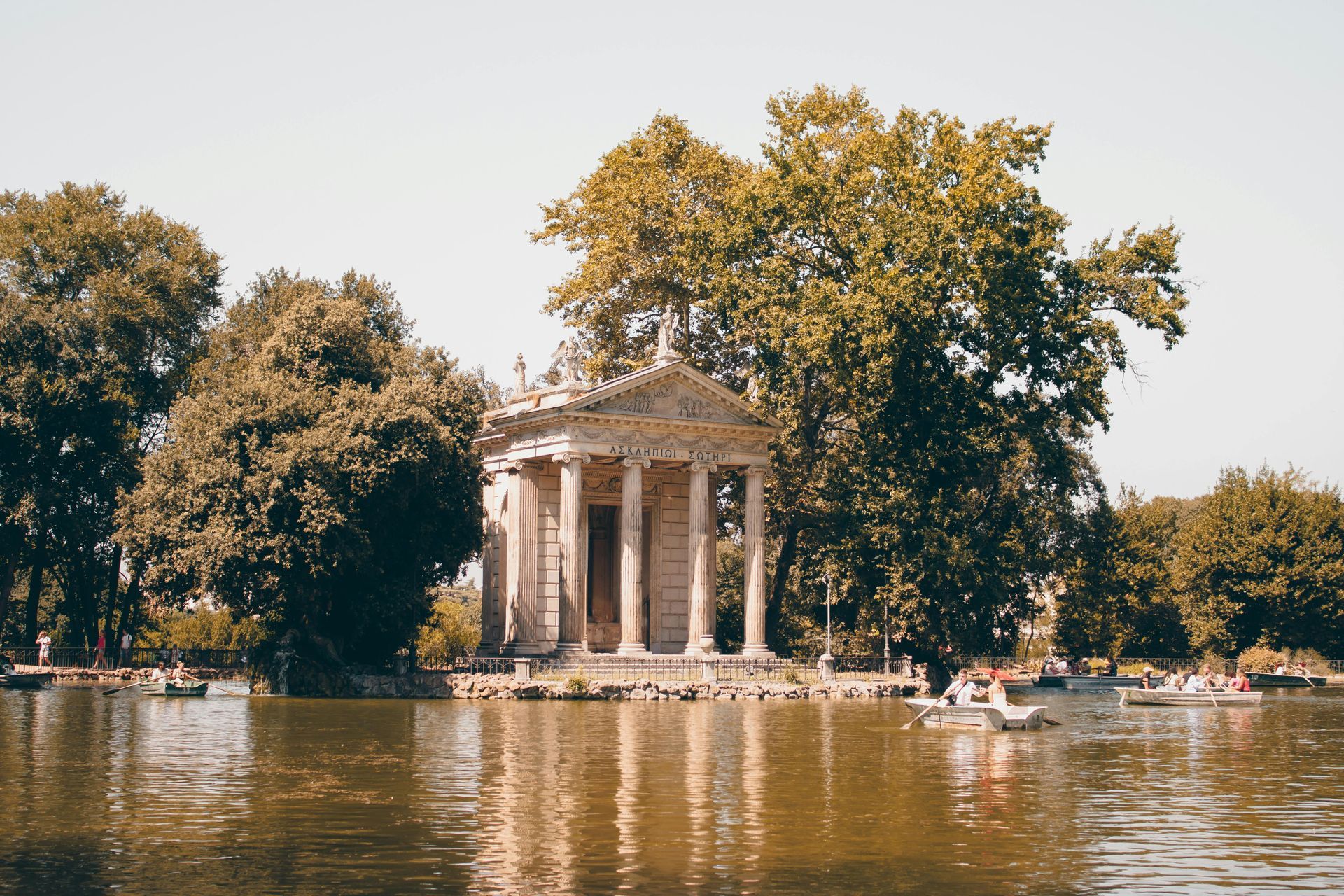 Scenic view of the Temple of Asclepius in Villa Borghese park with people boating on the pond