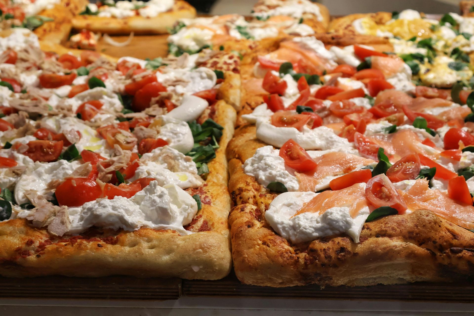 Freshly made Roman pizza with toppings of tomatoes, cheese, and greens, ready to be enjoyed in Monti
