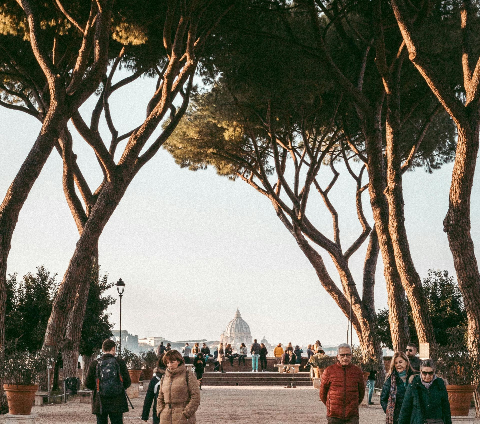 A scenic walk inGiardino degli Aranci with towering trees framing the view of St. Peter's Dome in the background