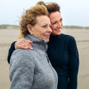 Deux femmes posent pour une photo sur la plage et l'une a son bras autour des épaules de l'autre