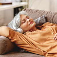 Une femme est allongée sur un canapé avec des écouteurs.