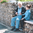 Un homme âgé avec une canne est assis sur un banc avec une petite fille