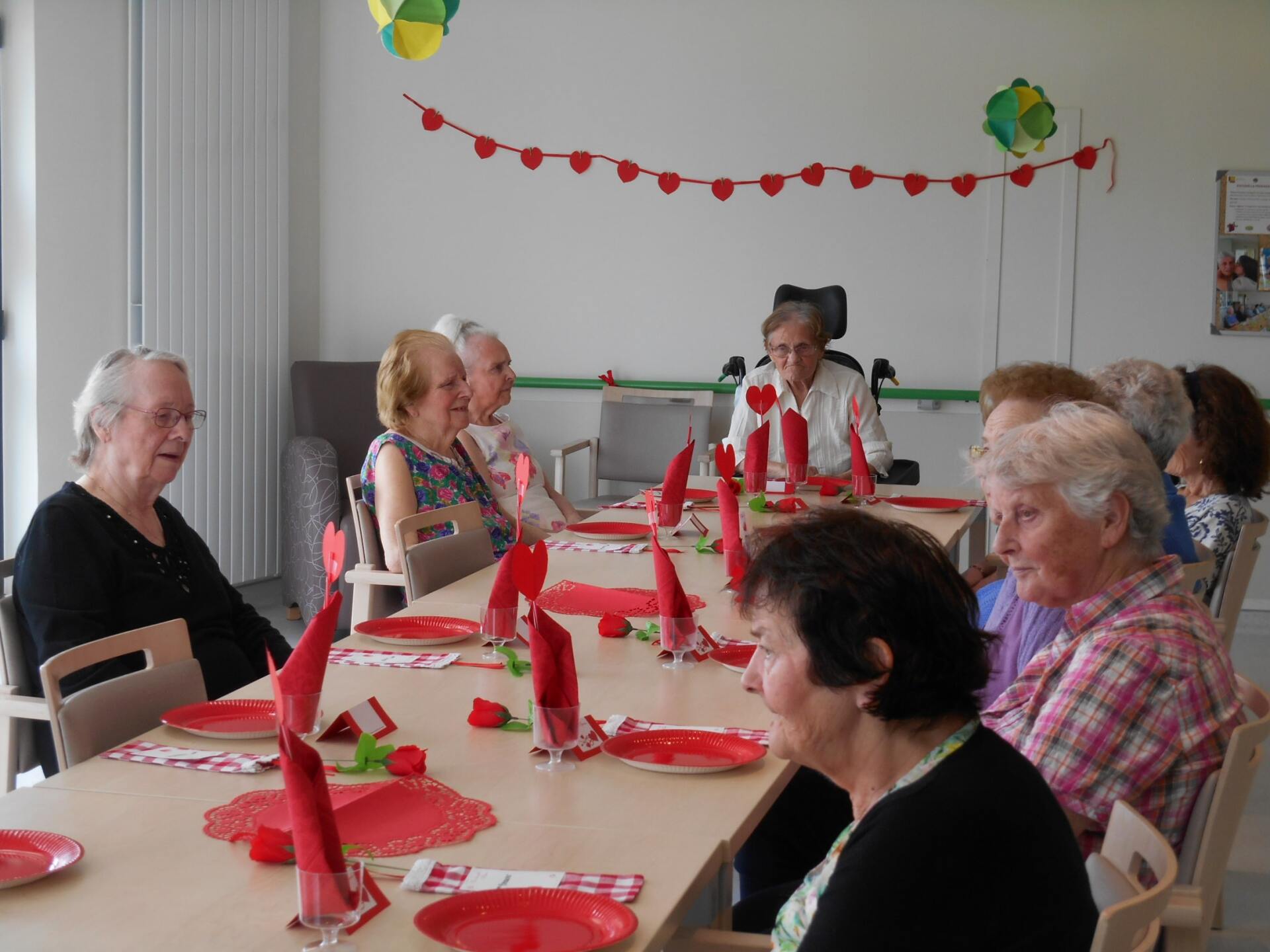 Un groupe de personnes est assis à une table avec des serviettes et des assiettes rouges.