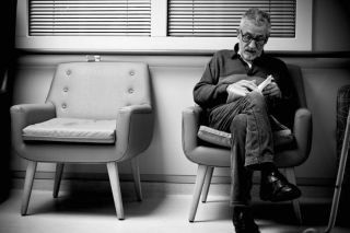Un homme est assis sur une chaise en train de lire un livre.