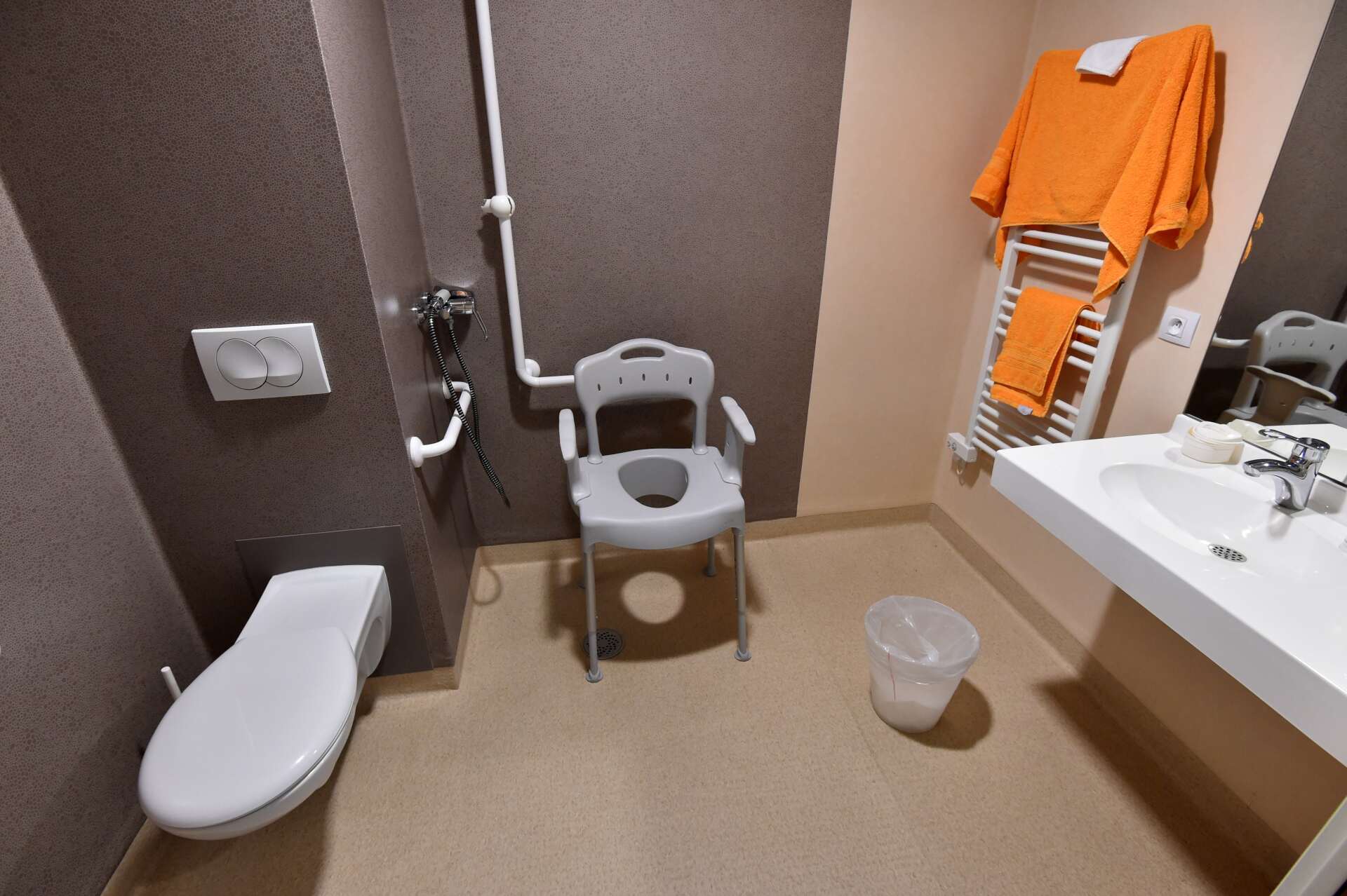 Une salle de bain avec toilettes, lavabo et chaise