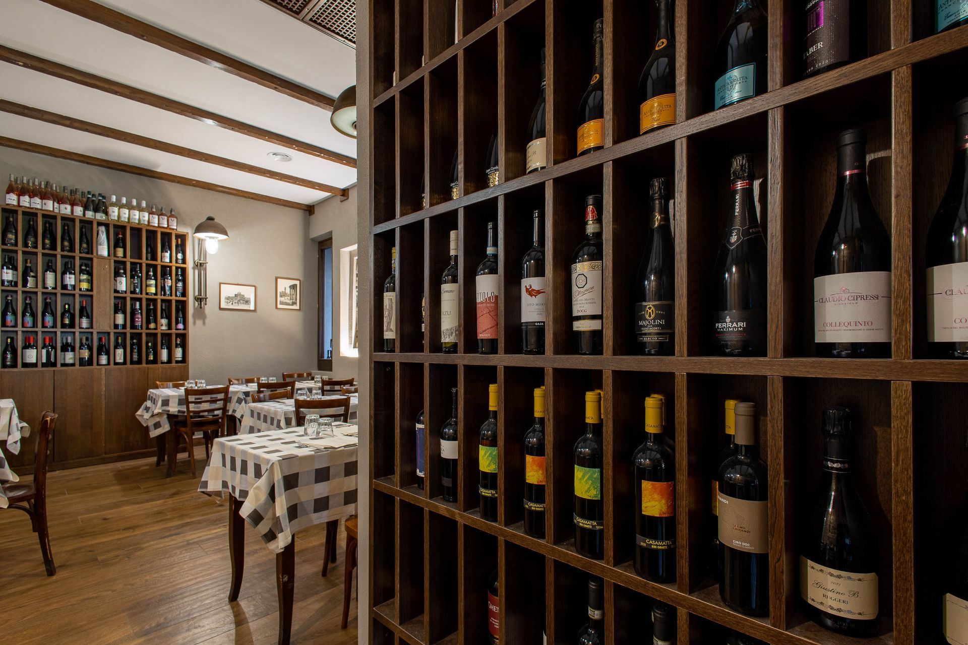Cantina con file di bottiglie sugli scaffali e tavoli a scacchi in una sala da pranzo rustica
