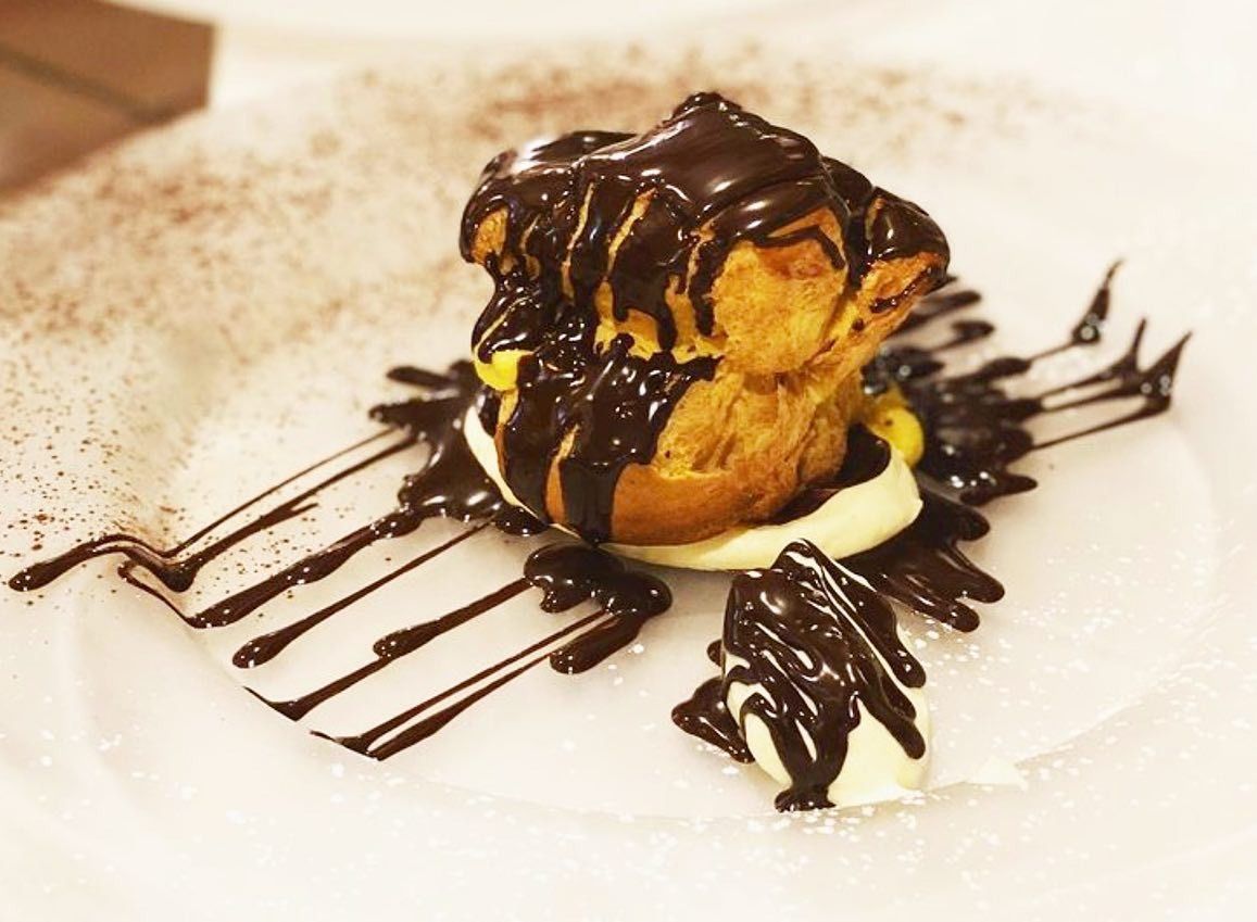 Dolce di pasta sfoglia con salsa al cioccolato e gelato, servito su un piatto bianco e guarnito con una colata di cioccolato fondente.