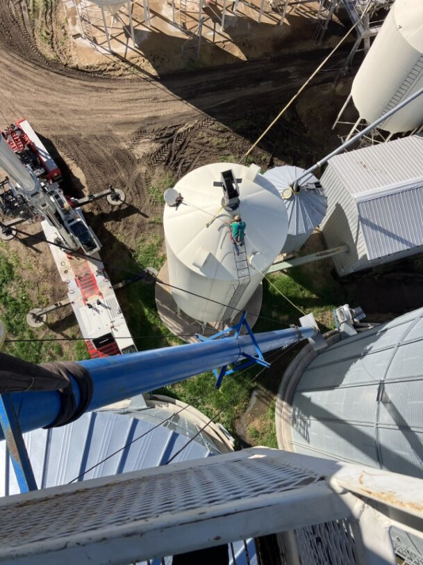 Person on a silo roof; a lift truck and other grain silos are in view at Coro View Farms Ltd.