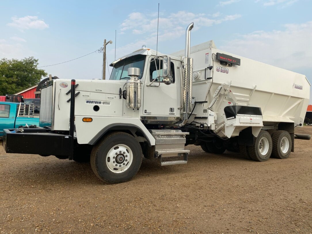White semi-truck with a large container on its bed, parked outside on a sunny day at Coro View Farms Ltd.