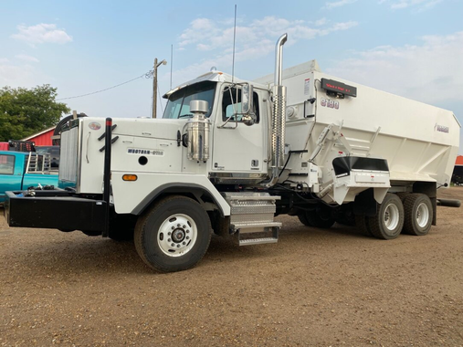 White semi-truck with a large container on its bed, parked outside on a sunny day at Coro View Farms Ltd.
