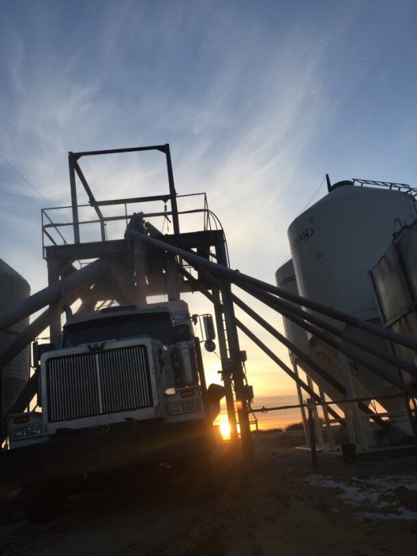 Truck unloading grain at silos, with a sunrise at Coro View Farms Ltd.