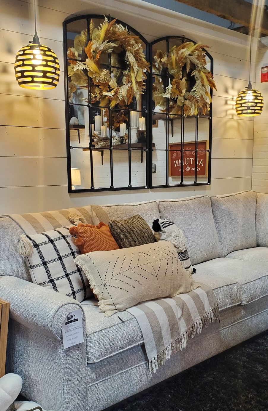 A couch with pillows and a mirror above it.