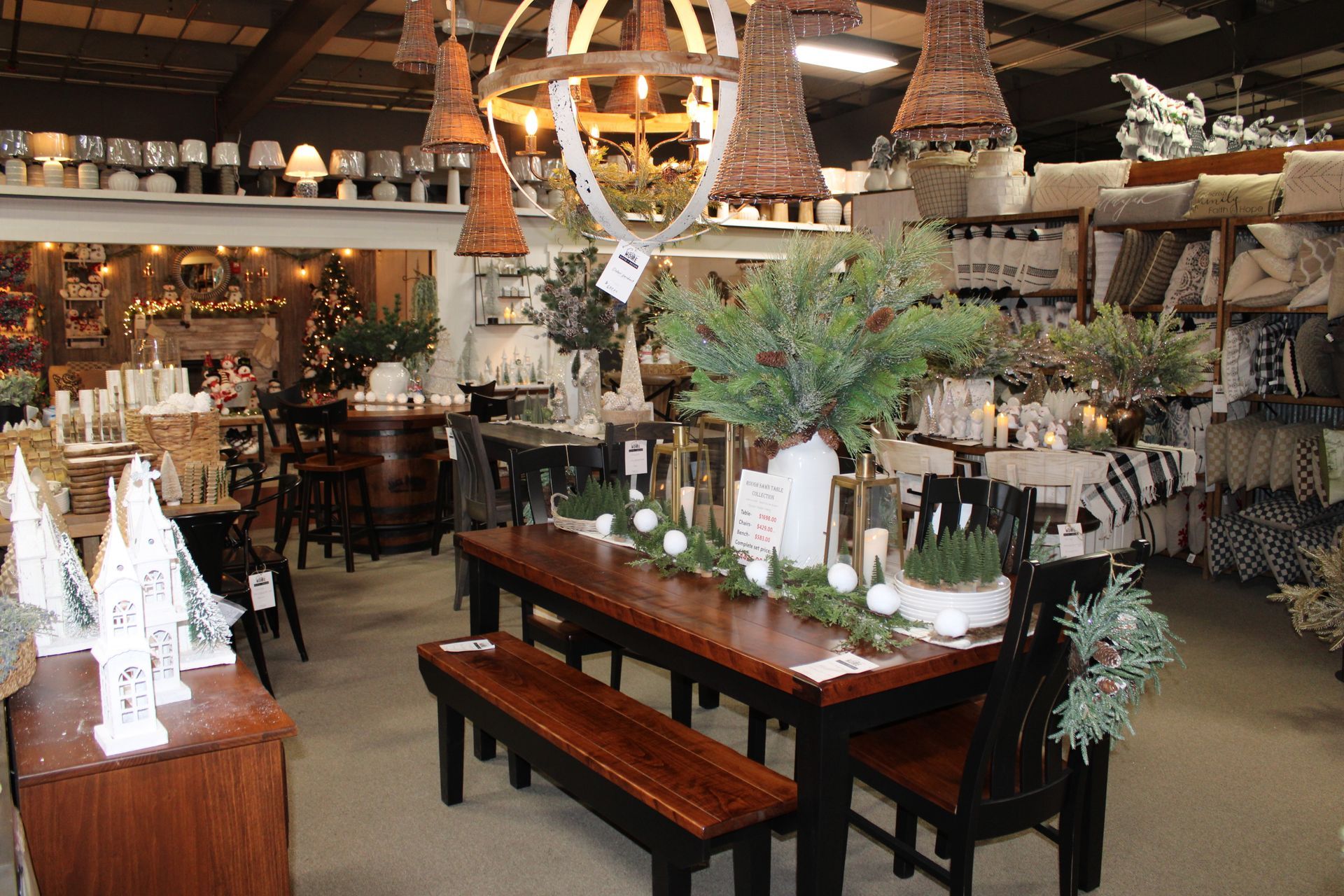 A home decor store display with a wooden dining table, greenery, ornaments, and a warm lighting set.