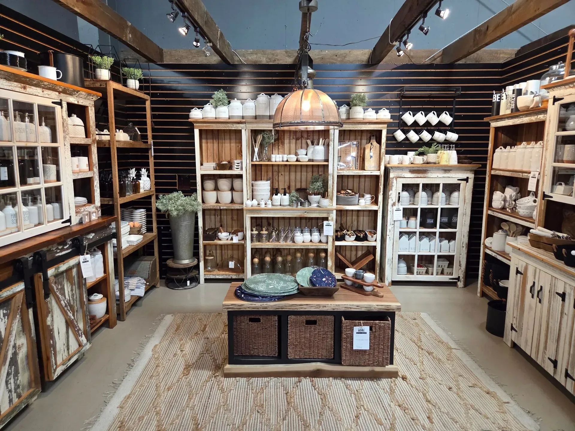 Rustic home decor store display with wooden shelves, ceramic pieces, and a central table.