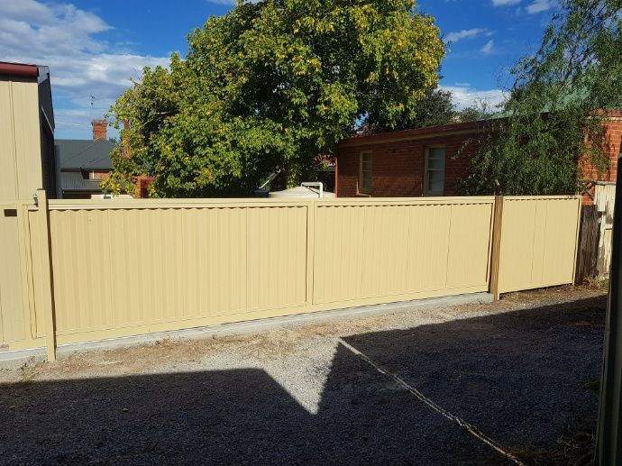 A Beige Metal Fence In Front Of A House — Anne & Ron Johnson Fencing in Werris Creek, NSW