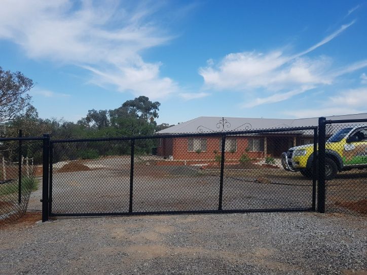 A Black Chain Link Fence Stands Tall With A Truck Parked In Front — Anne & Ron Johnson Fencing in Werris Creek, NSW