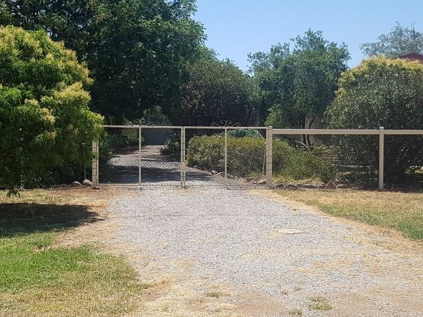 A Gravel Driveway With A Gate, Bordered By Trees And Secured By A Chain Wire Fence— Anne & Ron Johnson Fencing in Werris Creek, NSW