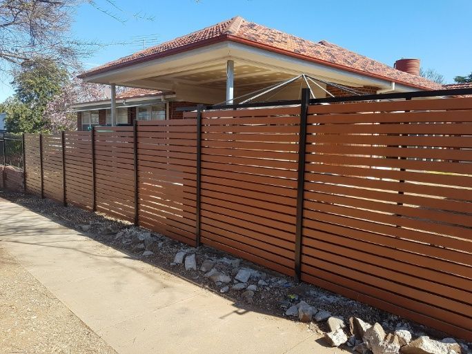 A Wooden Slat Fence Stands In Front Of A House — Anne & Ron Johnson Fencing in Werris Creek, NSW