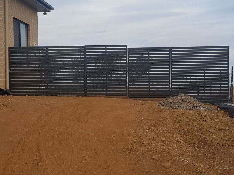 A Slat Fence Is Constructed Beside A House — Anne & Ron Johnson Fencing in Werris Creek, NSW