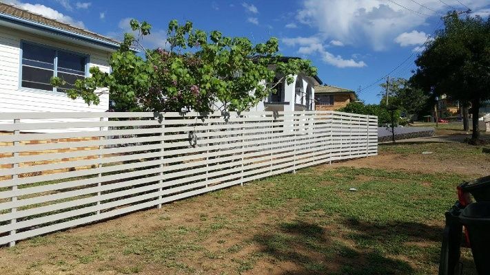 A Slat Fence Is Constructed Beside The House With A Tree In The Yard — Anne & Ron Johnson Fencing in Werris Creek, NSW