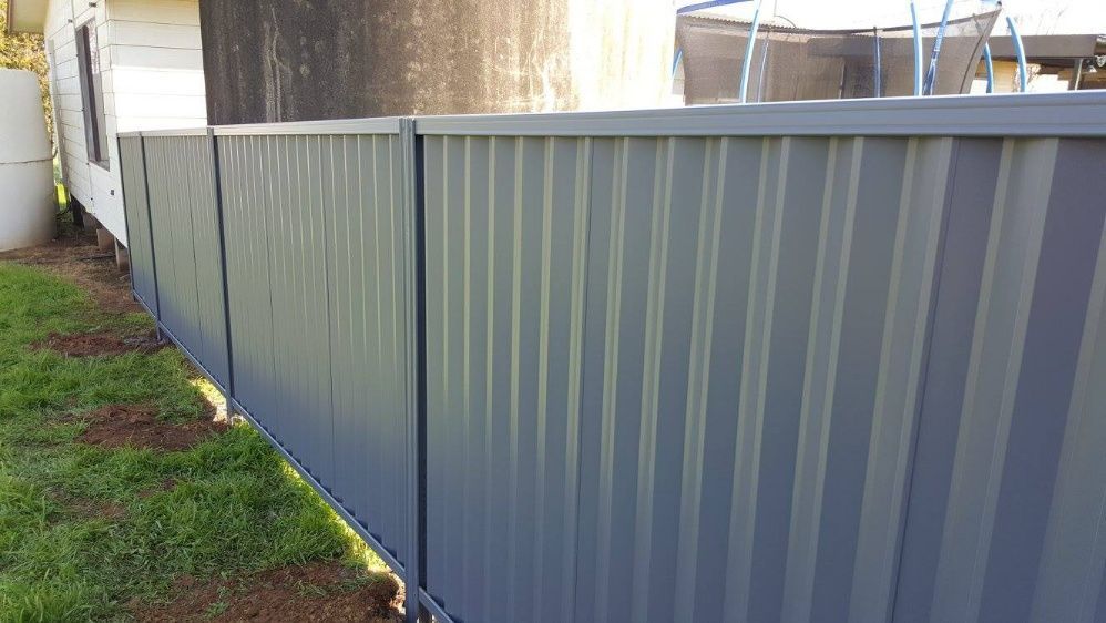 A Fence With A Blue Metal Panel Attached — Anne & Ron Johnson Fencing in Werris Creek, NSW