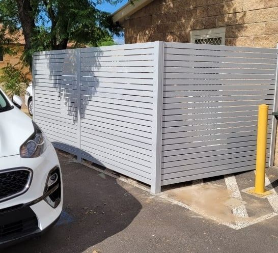 A White Car Parked In Front Of A Slat Fence — Anne & Ron Johnson Fencing in Werris Creek, NSW