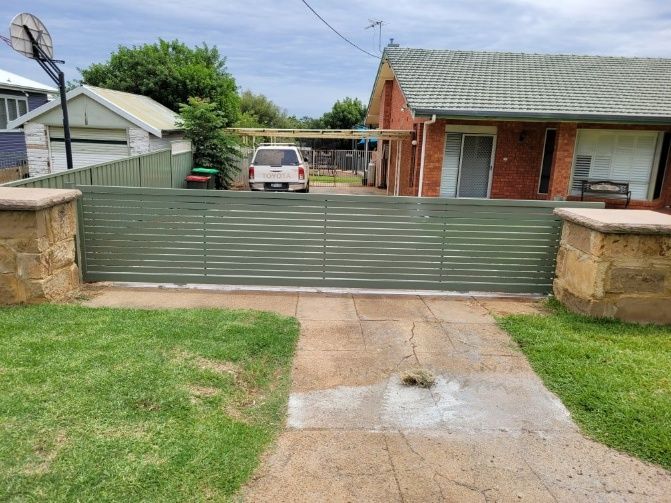 A House Is Framed By A Fence Featuring An Auto Gate — Anne & Ron Johnson Fencing In Werris Creek, NSW