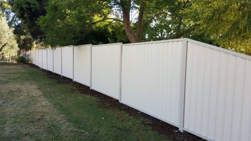 A White Fence Stands In Front Of Trees — Anne & Ron Johnson Fencing in Werris Creek, NSW